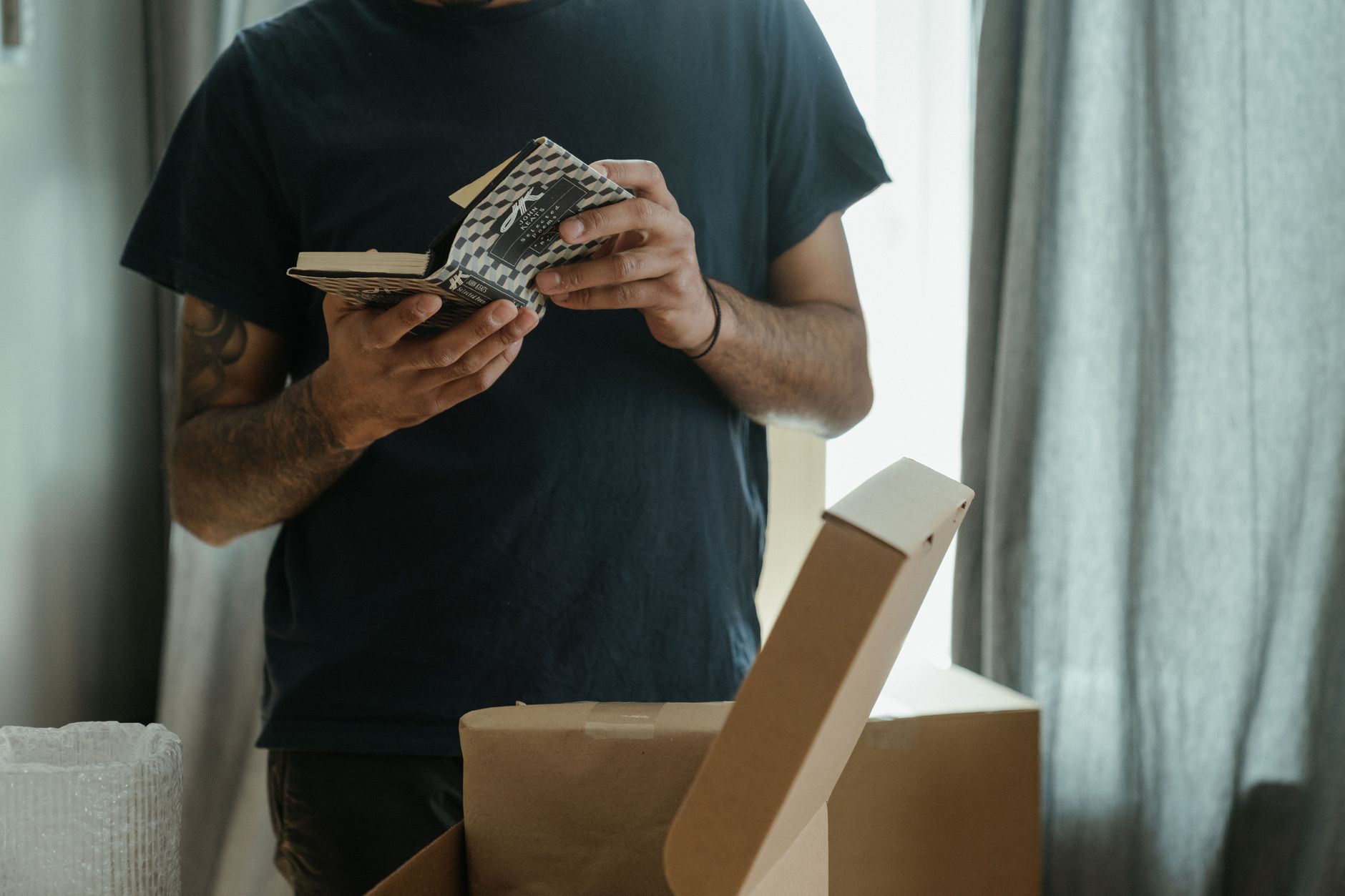 Cartons de déménagement posés devant une porte d'entrée, lettre administrative à la main